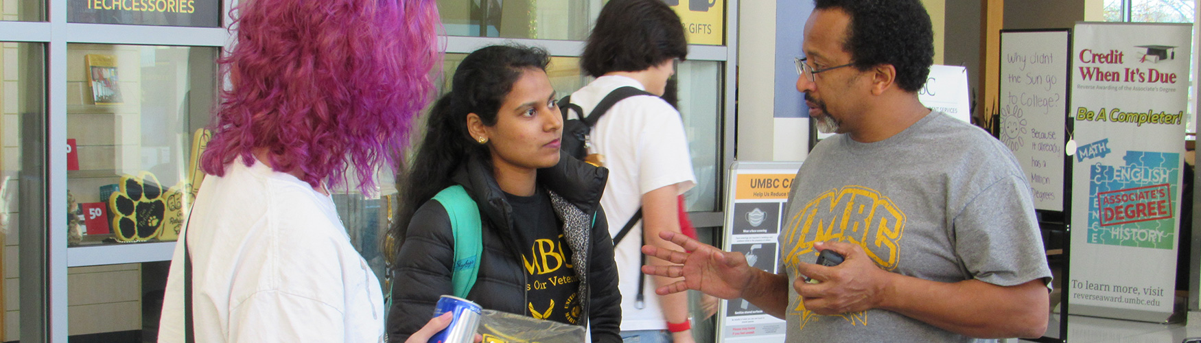 Veteran staff talking to two students at event