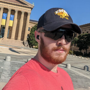 Man in UMBC hat and red shirt